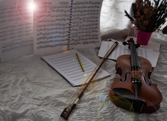 Violin and bow put at the right side of background,beside  blank note sheet and book,prepare for...