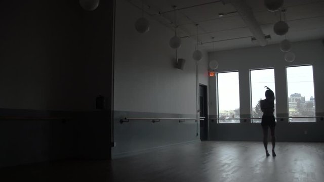 Modern contemporary dancer dancing in large minimal dance studio with windows in the background