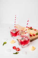 Refreshing strawberry cocktails and crushed ice on a gray background, vertical photo