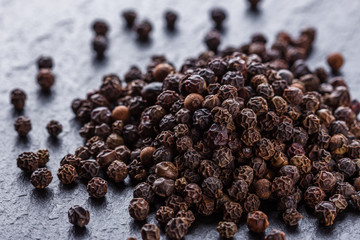 aromatic black pepper on a dark stone background