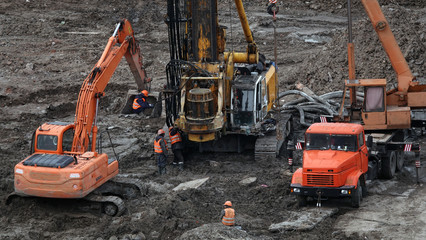 Workers repair equipment on the construction of the zero cycle foundation of the entertainment center