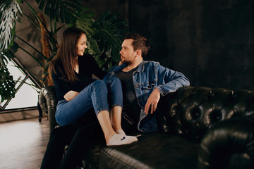 Fototapeta na wymiar a man sits on the couch with his woman, young lovers laugh and have fun