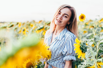 A young girl in a shirt stands in sunflowers