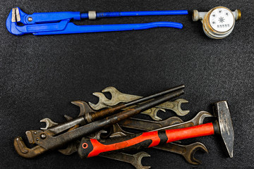 Hand tools for plumbing and parts on black background with space for advertising. Set for locksmith or plumber.