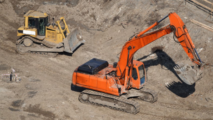 Tractors and excavators work on the construction of the foundation zero cycle