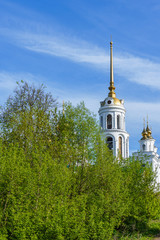 domes of an orthodox temple made of golden metal and the steeple of a bell tower against a blue sky