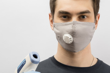 Young european man wearing mask against the corona virus and thumbs up covid 19 man wearing reusable surgical mask to prevent from virus white\grey background Corona virus pandemic funny fun