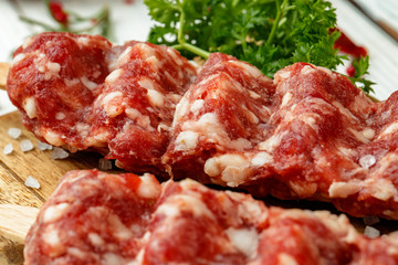 Raw lula kebab on skewers with spices on wooden board