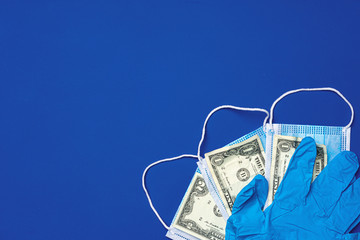 Close up of medical protective masks and american dollar banknotes on blue background