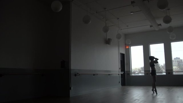Modern contemporary dancer dancing in large minimal dance studio with windows in the background and lots of atmosphere
