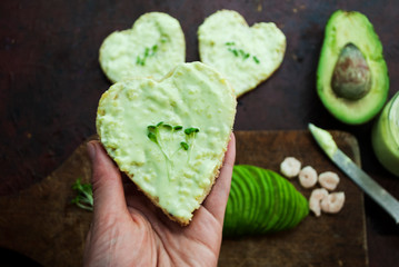 Someone eating gluten-free shrimp guacamole bread. Heart shaped sandwich in a female hand.