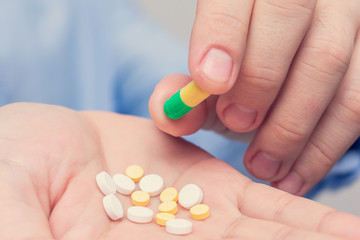 Pills in hand, man's hand and capsules, closeup, cropped image
