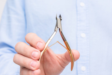 Man's hands shows nail clipper, close up. Concept of man's manicure