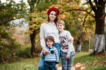 Fototapeta premium Such love, which is impossible to describe, only to feel. Mothers and sons. Happy Mother's Day! Mother hugs her children on a background of forest. Family. Mom and children are sitting on the mat.