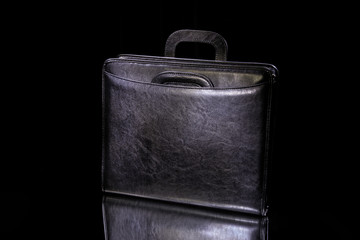 Black briefcase for papers and documents with handles and a clasp on a black background. Business...