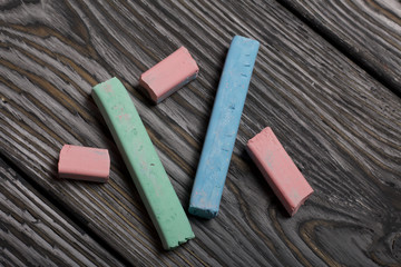 Pieces of chalk for drawing, different colors. They lie on pine boards painted with white and black paint.