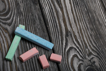Pieces of chalk for drawing, different colors. They lie on pine boards painted with white and black paint.