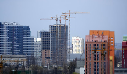 High-rise construction cranes on the background of houses in Kiev