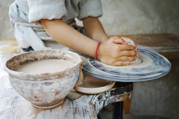 
little student makes a ceramic cup on a potter's wheel in a master class