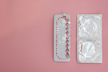 Contraceptive pills and condoms on colored background. View from above. Concept of birth control