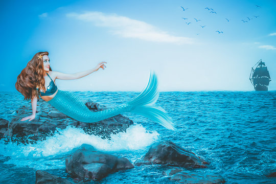 Beautiful mermaid on the stone in the blue sea closeup. Art processing