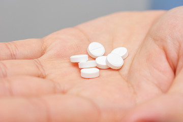 White pills in hand, a man's hand and a handful drugs, close-up, cropped image