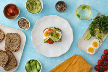 Smashed avocado on whole-grain toast to make avocado and tomato, egg sandwiches.