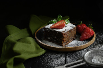Chocolate cake, strawberries. Dark background.