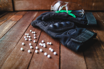 Glasses with dark gloves on the wooden background with scattered balls