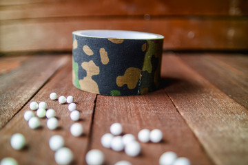 Scotch tape camouflage colors on a wooden background with balls, airsoft