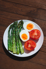 Breakfast with asparagus, egg and tomatoes. Vegetables. Food on wooden background.