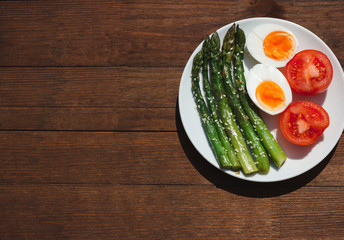 Breakfast with asparagus, egg and tomatoes. Vegetables. Food on wooden background.