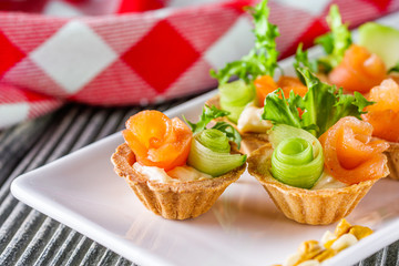 delicious snack tartlets on rustic wooden background