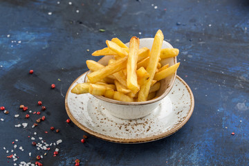 French fries in white bowl isolated on blue background