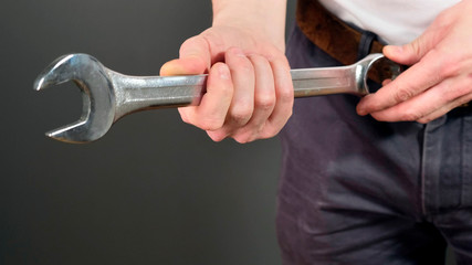 Male hand hold metal wrench. Close up.