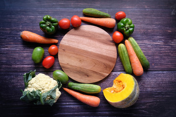 Healthy food selection with vegetables and empty chopping board on table 
