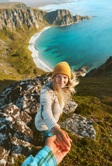 Naklejka na ściany i meble Cheerful woman follow holding hand her boyfriend couple travel vacations friends having fun outdoor hike tour in Norway adventure lifestyle aerial view ocean beach.