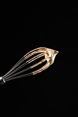 Woman barista making dalgona coffee. Metal whisk with cream from coffee and sugar. Culinary whisk in woman hand. Cold coffee drink and desert. Black background place for text banner.