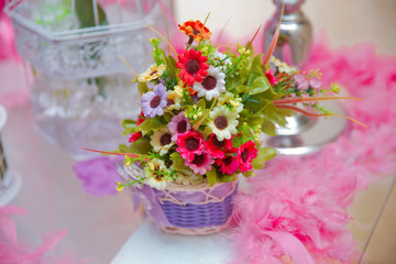 flower arrangements . The cage with flowers stand in restaurant . white roses put on the top of bird cage . Basket bouquet . Artificial multi-colored flowers .