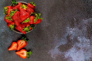 Delicious ripe strawberries in a plate on a gray background.