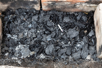 Close-up. Burned bonfire coals and an abandoned cigarette.