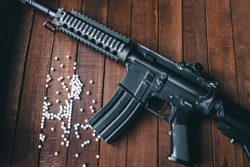 assault rifle lying on the wooden background with balls airsoft