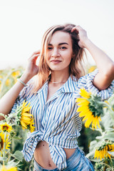 A young girl in a shirt stands in sunflowers