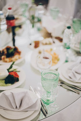 Fototapeta na wymiar Wedding luxury table setting at reception in restaurant. Stylish glasses for wine, plate with napkin, cutlery and food on tables. Luxury catering service. Christmas feast