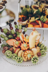 Delicious fresh fruits arranged in bird shape on table at wedding reception in restaurant. Luxury catering service. Wedding healthy fruit bar. Banana, oranges,grapes,peach, and apples