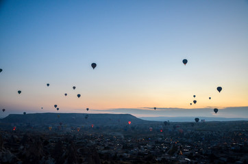 Hot air balloons at sunrise flying in the sky along valleys at Cappadocia of Goreme, Turkey 
