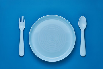 Plastic blue cutlery set with blue background. Top view