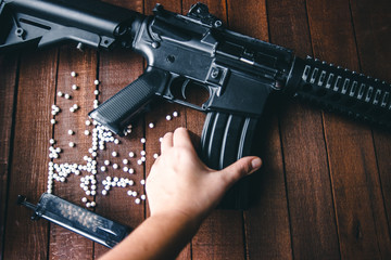 hand holds airsoft rifle, a wooden background