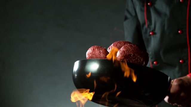 Super slow motion of flying raw hamburger steaks from wok pan. Filmed on high speed cinema camera, 1000 fps.