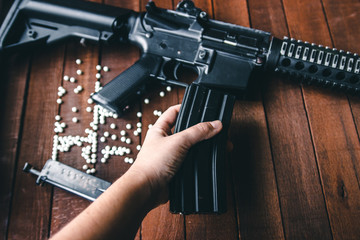 on wooden background hand holds a detail of airsoft assault rifle